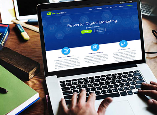 Hands typing on a silver laptop with the “Electroletter” digital marketing website open on screen